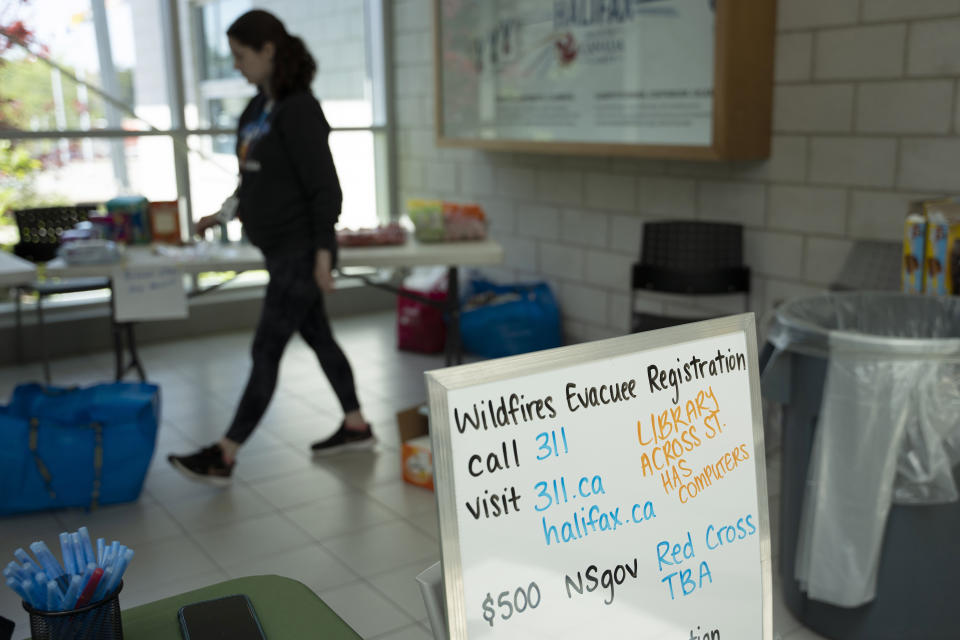 A sign directing evacuees is seen as volunteers and workers set up an evacuation centre where food and shelter is being provided for those forced from their homes due to the wildfire burning in suburban Halifax, Nova Scotia, Tuesday, May 30, 2023. (Darren Calabrese/The Canadian Press via AP)