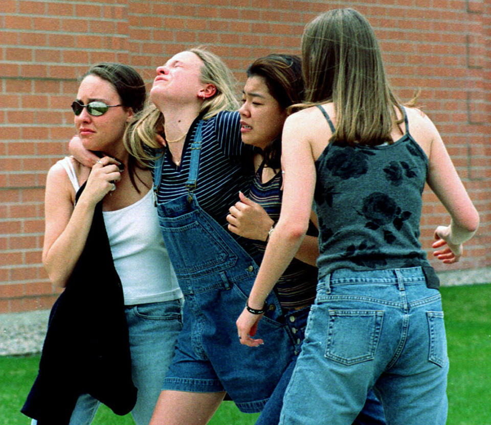 FILE - Young women head to a library near Columbine High School where students and faculty members were evacuated after two gunmen went on a shooting rampage in the school in the southwest Denver suburb of Littleton, Colo. Twenty-five years later, The Associated Press is republishing this story about the attack, the product of reporting from more than a dozen AP journalists who conducted interviews in the hours after it happened. The article first appeared on April 22, 1999. (AP Photo/Kevin Higley, File)