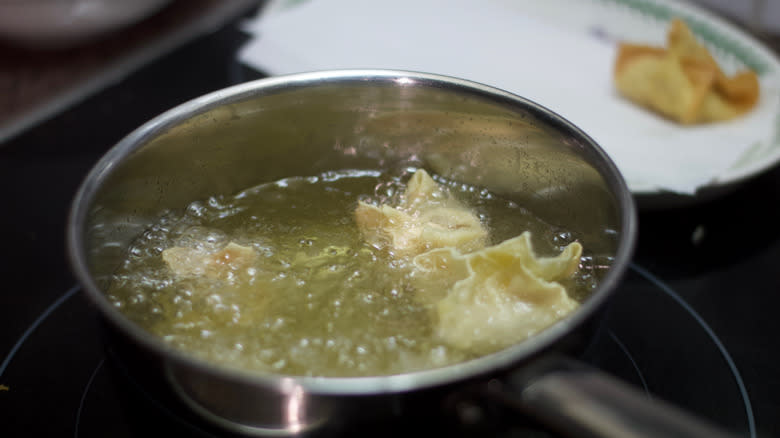 Wontons frying in pot of oil