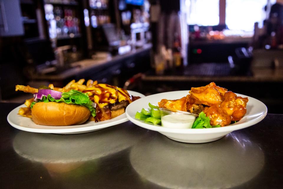 The Alabama burger, left, and a plate of Buffalo chicken wings are options at 2 Dogs Pub in Iowa City. The burger is an angus beef patty with jalapeños, bacon, caramelized onions, cheddar cheese, and a chipotle citrus barbecue sauce