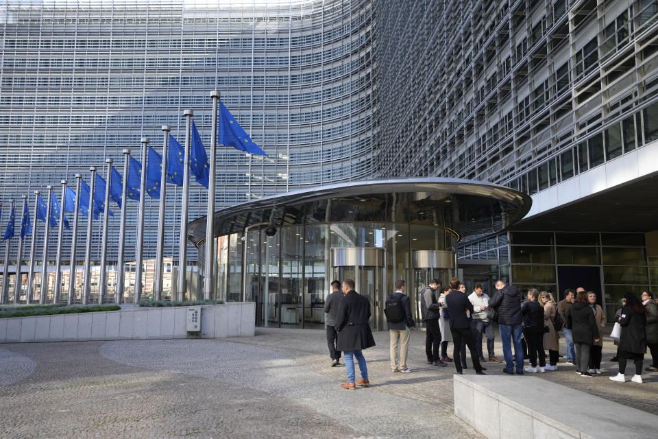 European Union flags flutter in the wind as people stand outside EU headquarters, after a shooting on Monday in the center of Brussels, Tuesday, Oct. 17, 2023. Police in Belgium have shot dead a suspected Tunisian extremist accused of killing two Swedish soccer fans in a brazen attack on a Brussels street. European Union institutions are currently remaining closed after a terror alert for Brussels was raised overnight to 4, the top of Belgian's scale, indicating an extremely serious threat. (AP Photo/Virginia Mayo)