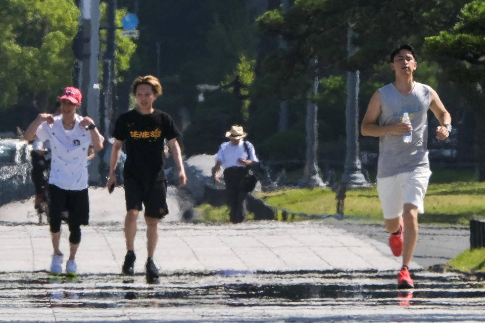 This picture taken on June 29, 2022 shows a man (R) running in a park around the Imperial Palace in a heat wave in Tokyo. (Photo by Kazuhiro NOGI / AFP) (Photo by KAZUHIRO NOGI/AFP via Getty Images)
