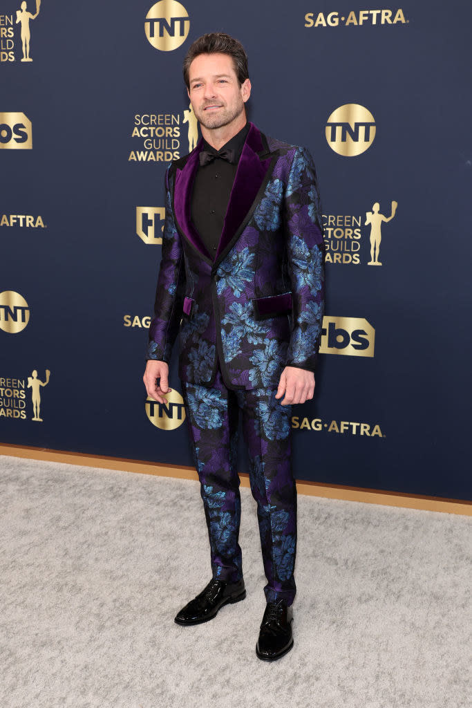 a uniquely colored, shiny paisley tux over a sold shirt and bowtie