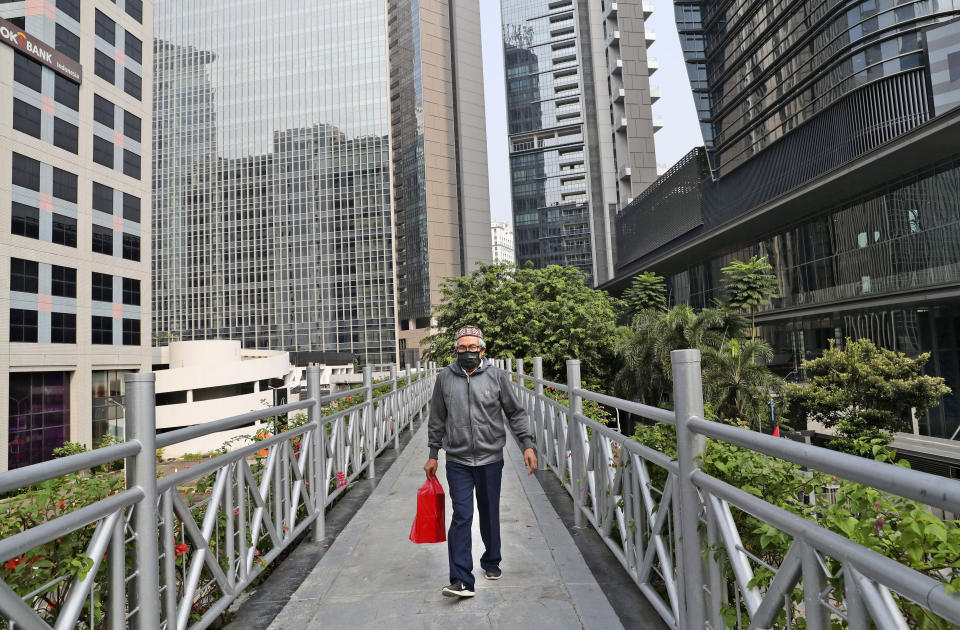 A man, wearing a face mask as a precaution against the new coronavirus outbreak, walks on a pedestrian bridge at the main business district in Jakarta, Indonesia, Monday, Sept. 14, 2020. Indonesia's capital on Monday begins to reimpose large-scale social restrictions to control a rapid expansion in the virus cases. (AP Photo/Tatan Syuflana)