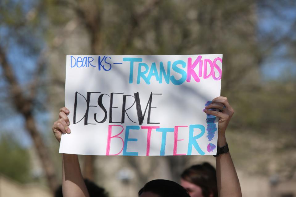 A protestor displays a sign supporting transgender youth at a Statehouse rally on April 13, days after lawmakers overrode Gov. Laura Kelly's veto on a bill banning trans athletes from women's sports in Kansas.