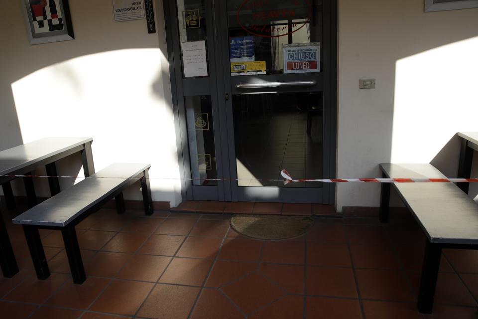 Red and white tape cordons off the cafe where three people who frequented it tested positive for the China virus, in Castiglione d'Adda, Northern Italy, Saturday, Feb. 22, 2020. A dozen northern Italian towns were on effective lockdown Saturday after the new virus linked to China claimed two fatalities in Italy and sickened an increasing number of people who had no direct links to the origin of the virus. (AP Photo/Luca Bruno)