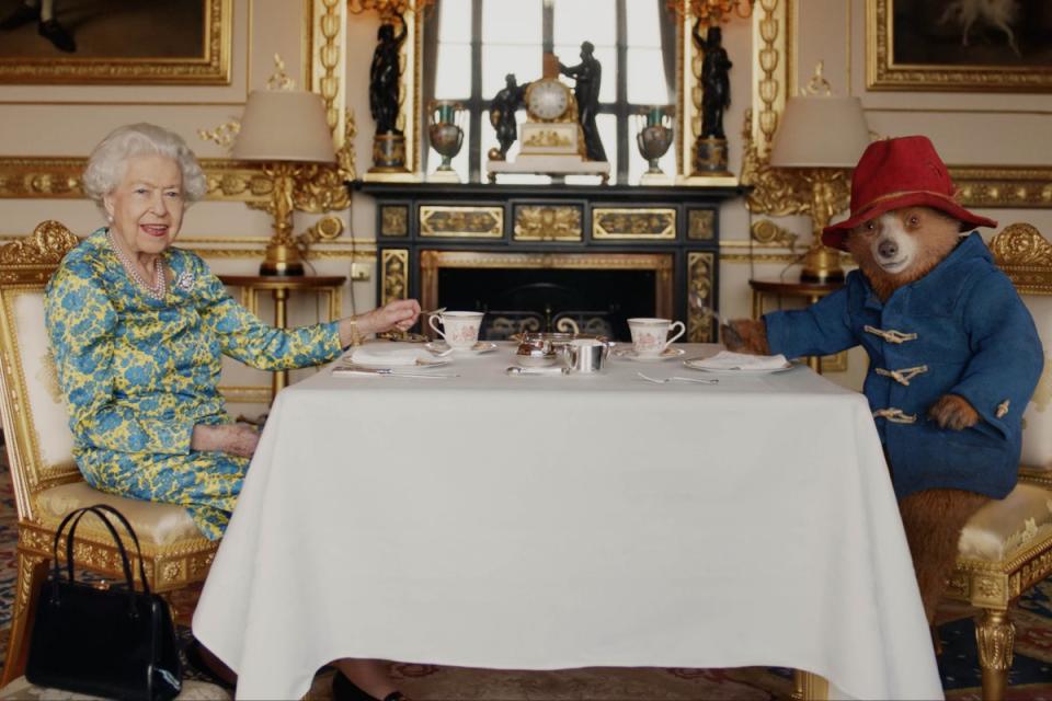 Queen Elizabeth II and Paddington Bear having cream tea at Buckingham Palace (PA)