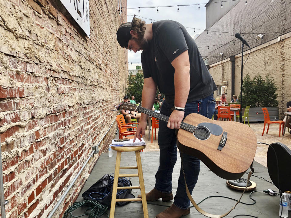 Marshall football player Will Ulmer goes over his playlist during a concert July 18, 2021, in Huntington, W.Va. Will Ulmer doesn’t have to hide anymore. The Marshall offensive lineman, all 6-foot-4 and 300 pounds of him, unleashed a year's worth of energy in his first on-stage performance since the start of the pandemic, playing guitar and belting out songs in his Kentucky baritone for a modest crowd outside a Huntington ice cream store..(AP Photo/John Raby)