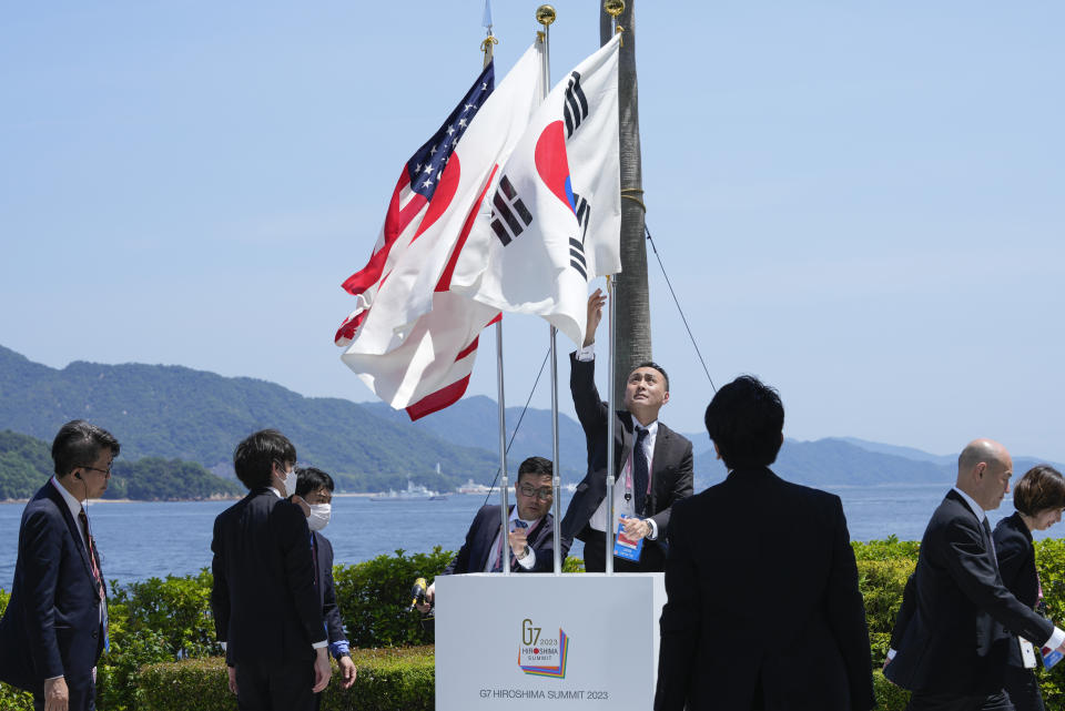 Officials attempt adjust flags during the G7 Summit in Hiroshima, Japan, Sunday, May 21, 2023. (AP Photo/Susan Walsh)
