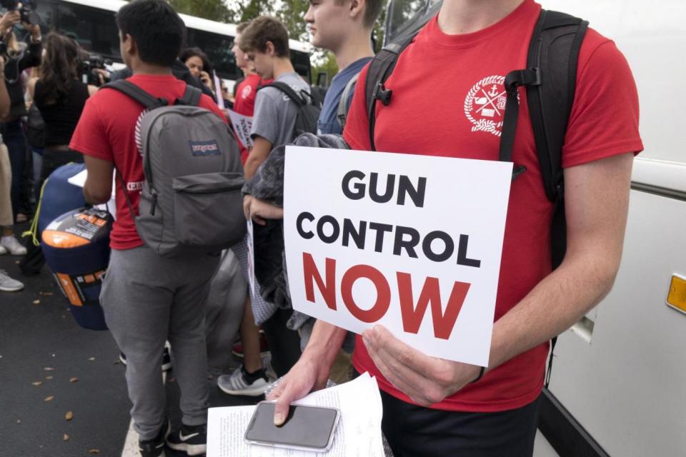 Proitest: Students from Marjory Stoneman Douglas High School hold signs while waiting to board buses in Parkland, Florida (EPA)