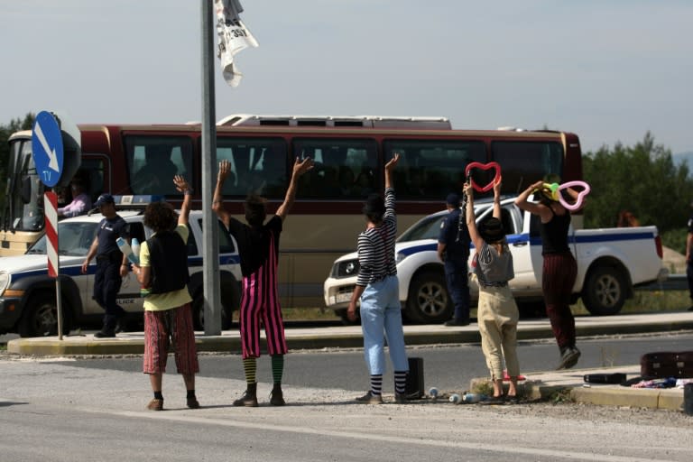 Clowns from a solidarity group wave as migrants are evacuated from the makeshift camp at the Greek-Macedonian border, near Idomeni, on May 24, 2016