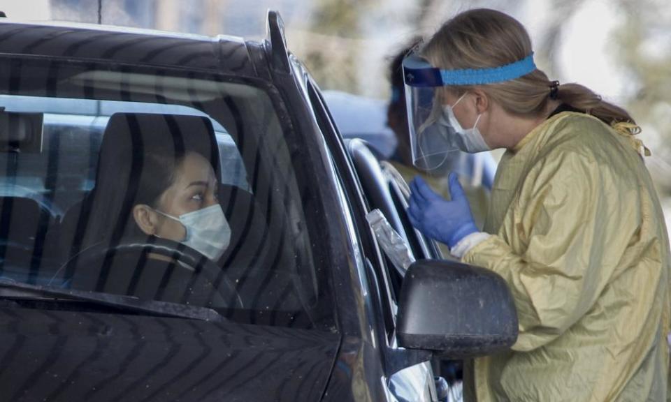 An Alberta health services employee speaks with a motorist at a drive-thru coronavirus testing facility in Calgary, Alberta.