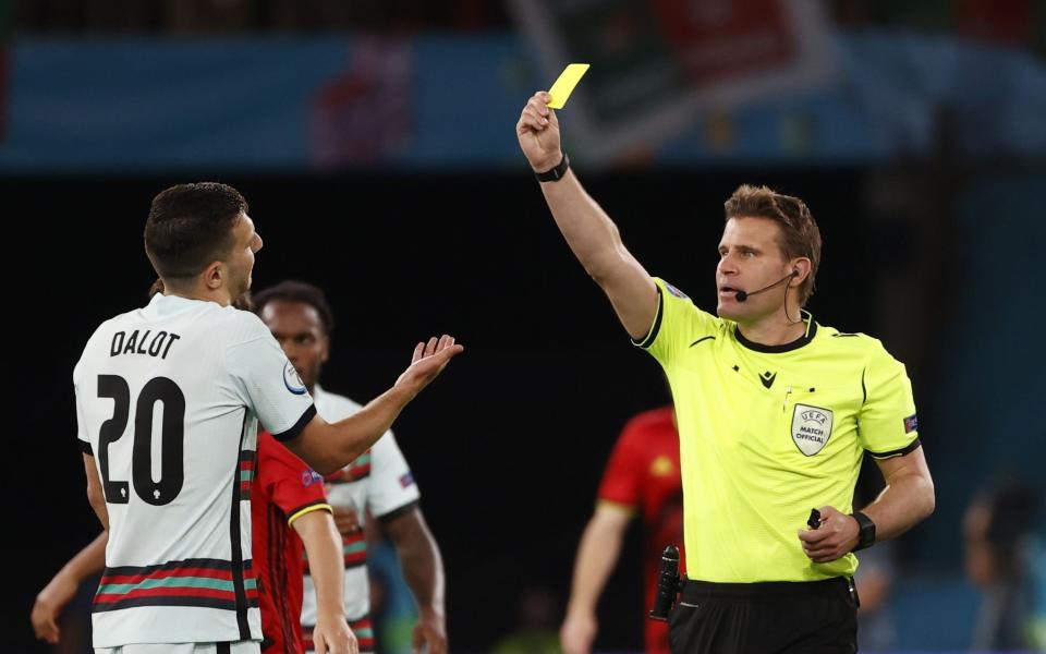 German referee Felix Brych shows the yellow card to Diogo Dalot - Shutterstock