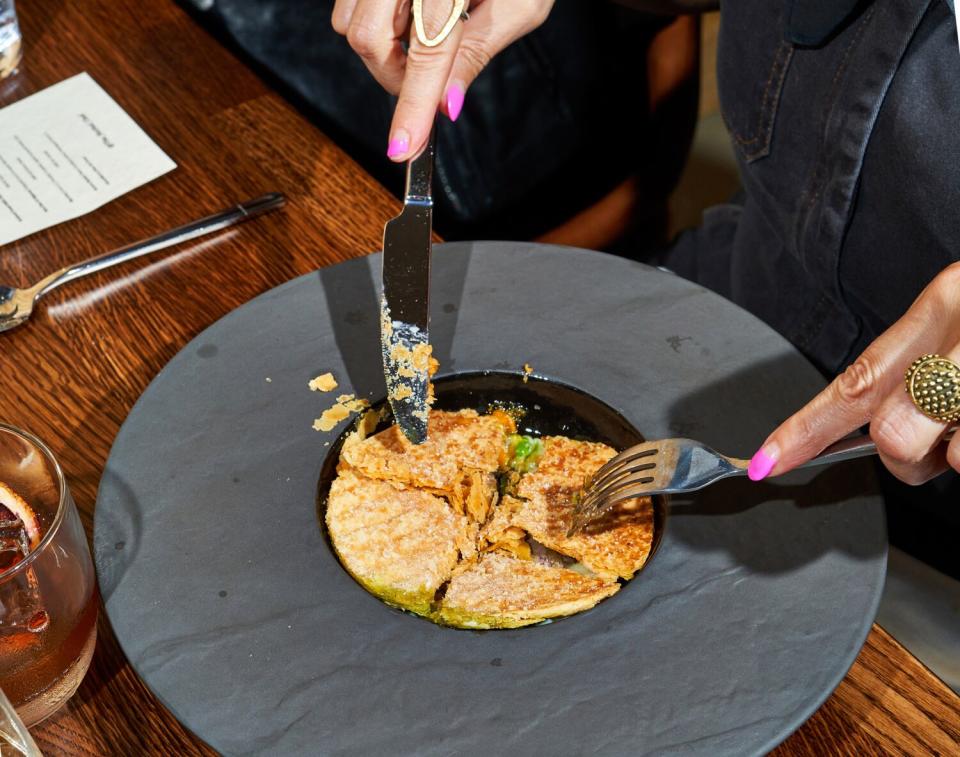 A puff pastry served in a black, wide-rimmed plate that resembles an upside-down hat.