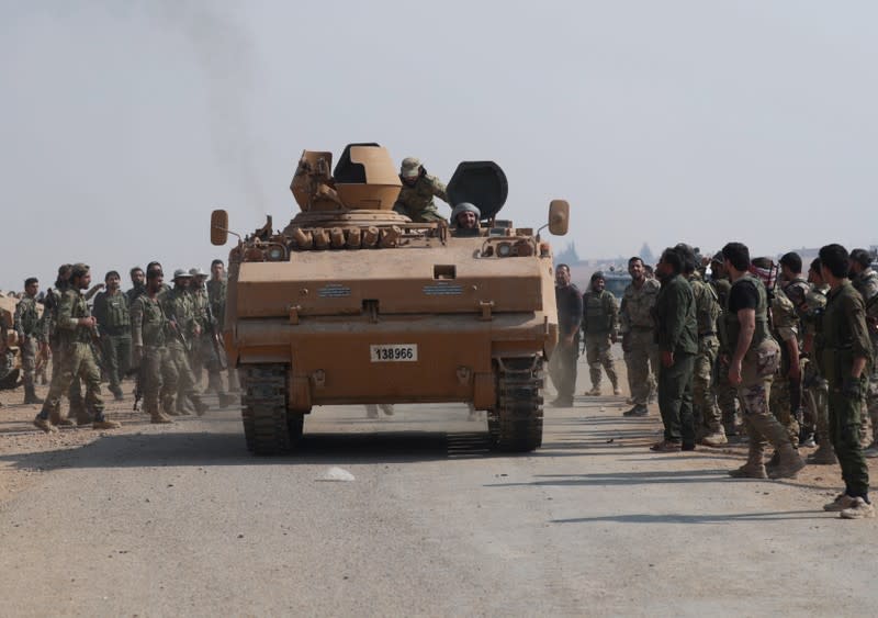 Turkey-backed Syrian rebel fighters gather as a military vehicle advances near the border town of Tal Abyad