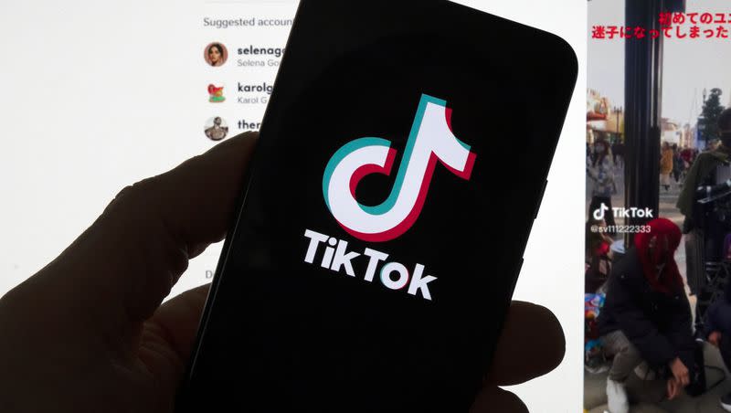 The TikTok logo is seen on a mobile phone in front of a computer screen which displays the TikTok home screen on March 18, 2023, in Boston.