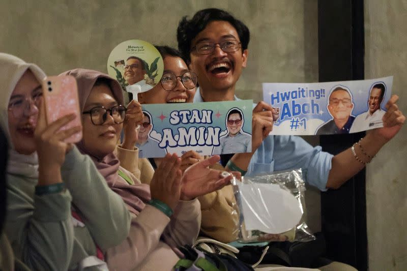 People react while watching a debate during the Humanies Cup Sleeve Event at the Kopi Nako cafe in Jakarta