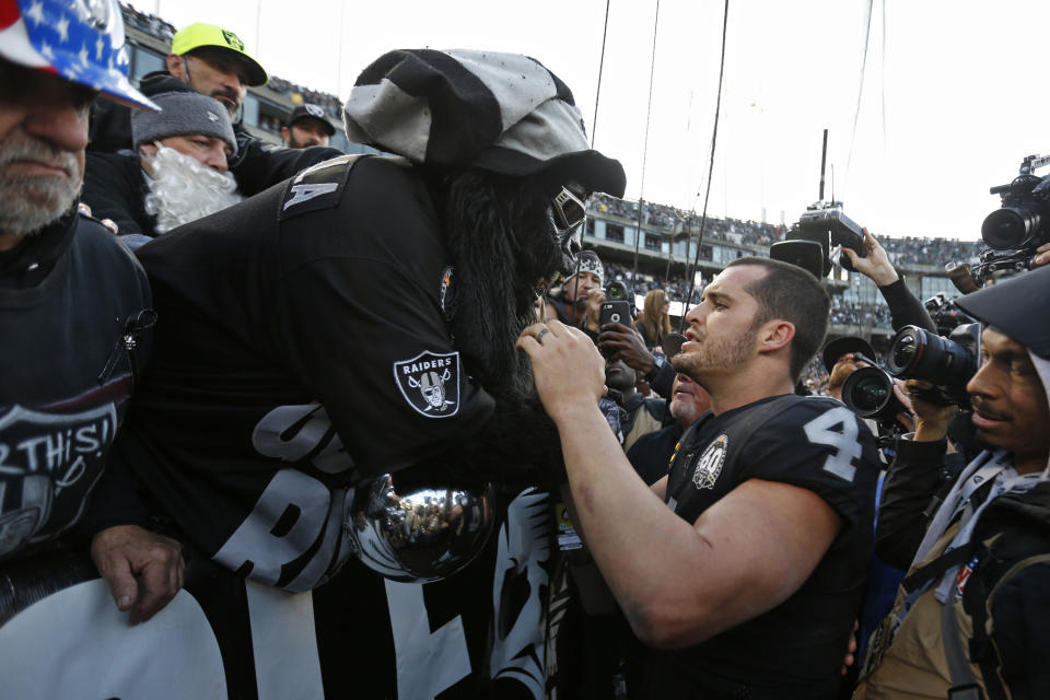 Oakland Raiders quarterback Derek Carr (4) is met by Gorilla Nilla in "The Black Hole" at the end of an NFL football game against the Jacksonville Jaguars in Oakland, Calif., Sunday, Dec. 15, 2019. (AP Photo/D. Ross Cameron)