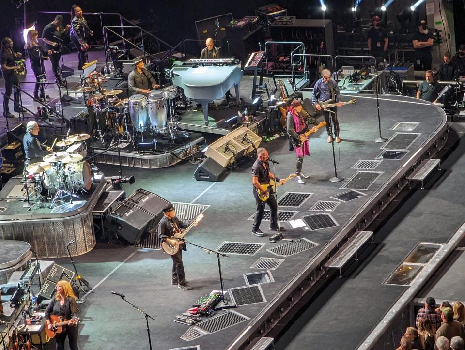 The core of The E Street Band remains 50-ish year members Max Weinberg, on drums; Roy Bittan, on piano; Little Steven Van Zandt, in the flowing scarves, on guitar; and Garry Tallent, top right, on bass. Weinberg and Bittan joined in 1974, leading up to recording of Springsteen's third album, "Born to Run." Van Zandt had been a band member and friend since childhood, but had formed his own group, Southside Johnny and the Asbury Jukes, while Springsteen was landing a recording contract with Columbia Records, touted as the "new Dylan." Van Zandt, also known as Miami Steve due to his flamboyant fashion style, became an official E Streeter in 1975, helping arrange horns and create guitar lines for the "Born to Run" album. Aside from Springsteen, Tallent, at top right, is the only all-time E Street Band member, having worked with him since 1971, and been one of the original E Street Band, which formed in '72. Guitarist Nils Lofgren, wearing the Greek sailor's cap, is the next-up veteran, an E Streeter since 1984, joining for the "Born in the U.S.A" tour, while Van Zandt worked on solo and other group projects. Soozie Tyrell, on guitar at bottom left, though her main instrument's violin,  has played and sung with Springsteen since 1992. The percussionist shown, to the left of Bittan's grand piano, is Anthony Almonte, who's worked largely with Latin musicians, but also with Van Zandt's '80s-born Disciples of Soul band. Up top are the four background singers on the tour, from left, Curtis King, who's worked with Springsteen since 2006; Lisa Lowell, who's sung with him since '92; Ada Dyer, veteran singer whose credits reach back to Chaka Khan and Lenny Kravitz, a more recent E Streeter; and Michelle Moore, who's been with them since 2012. Cropped from this picture are keyboardist Charles Giordano, who stepped up after Federici's death in 2006, and the five-piece horn section, which includes Clarence's nephew Jake Clemons on saxophone.