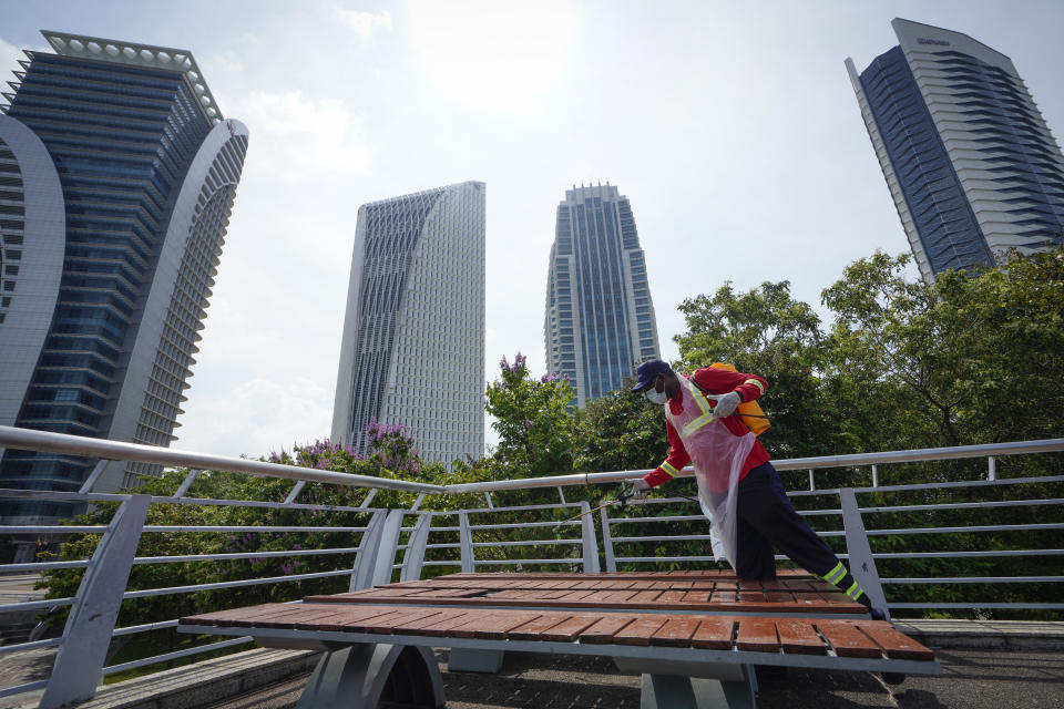 City hall workers spray disinfectant in Putrajaya, Malaysia, on Monday, Oct. 19, 2020. Malaysia restrict movements in its biggest city Kuala Lumpur, neighboring Selangor state and the administrative capital of Putrajaya from Wednesday in an attempt to curb a sharp rise in coronavirus cases. (AP Photo/Vincent Thian)