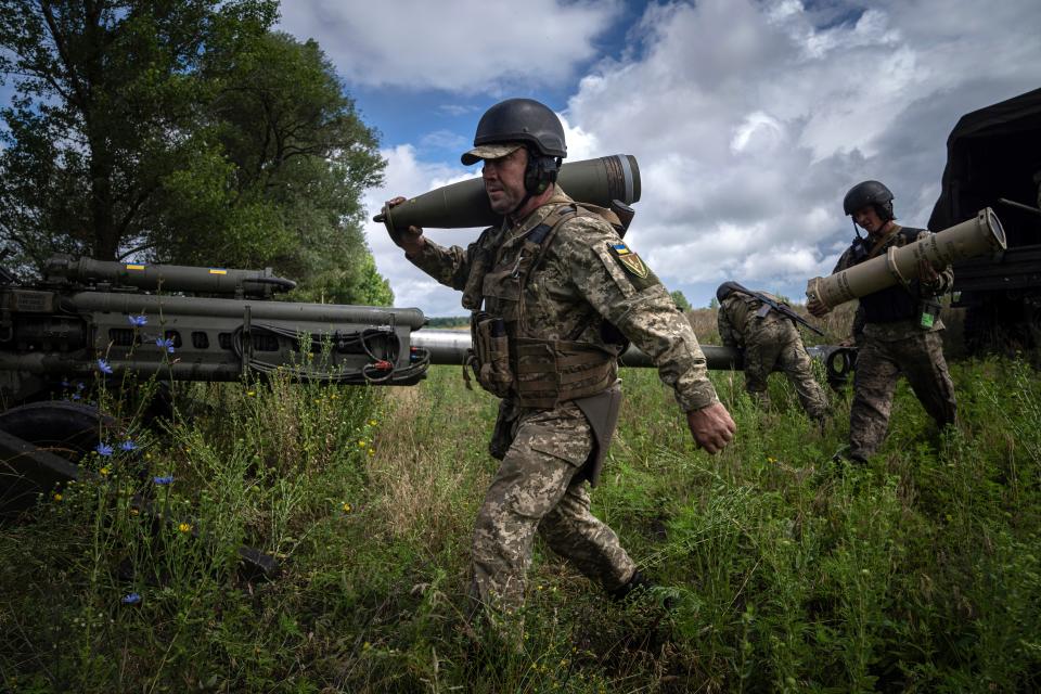 A Ukrainian serviceman carries a 155 mm artillery shell before firing at Russian positions from a U.S.- supplied M777 howitzer in Kharkiv region, Ukraine, Thursday, July 14, 2022.