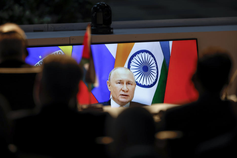 A screen shows Russian President Vladimir Putin via video link delivering remarks as delegates look on while attending a meeting during the 2023 BRICS Summit at the Sandton Convention Centre in Johannesburg Thursday, Aug. 24, 2023. (Marco Longari/Pool via AP)