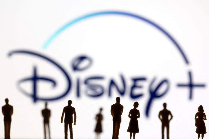 FOTO DE ARCHIVO: Figuras de personas se ven delante del logotipo Disney+ desplegado en esta ilustración