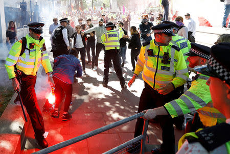 A police officer holds a flare during demonstrations outside Downing Street ahead of the visit by Turkey's President Recep Tayyip Erdogan, in London, Britain, May 15, 2018. REUTERS/Peter Nicholls