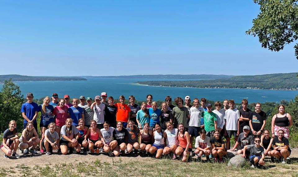 Members of the Boyne City, Charlevoix, Cheboygan and Inland Lakes cross country teams gather at the top of Avalanche Mountain in Boyne City, overlooking the lake that separates the rival Ramblers and Rayders.