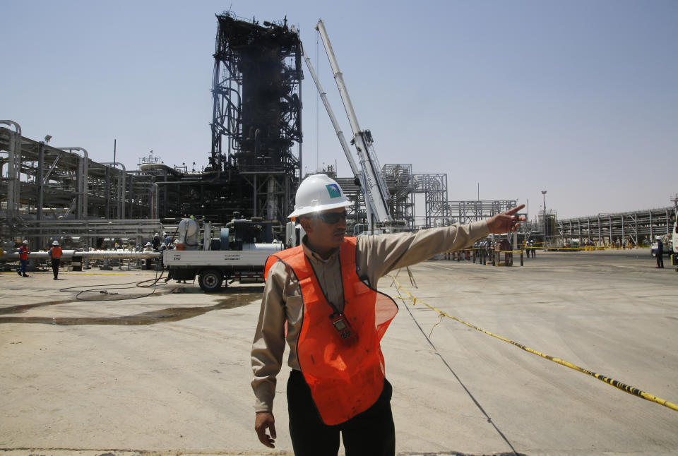In this photo opportunity during a trip organized by Saudi information ministry, a worker points in front of the Khurais oil field in Khurais, Saudi Arabia, Friday, Sept. 20, 2019, after it was hit during Sept. 14 attack. Saudi officials brought journalists Friday to see the damage done in an attack the U.S. alleges Iran carried out. Iran denies that. Yemen's Houthi rebels claimed the assault. (AP Photo/Amr Nabil)