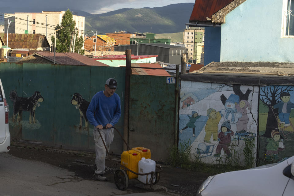 A man pushes a trolley of containers past murals outside a home in the Ger District on the outskirts of Ulaanbaatar, Mongolia, Thursday, June 27, 2024. (AP Photo/Ng Han Guan)