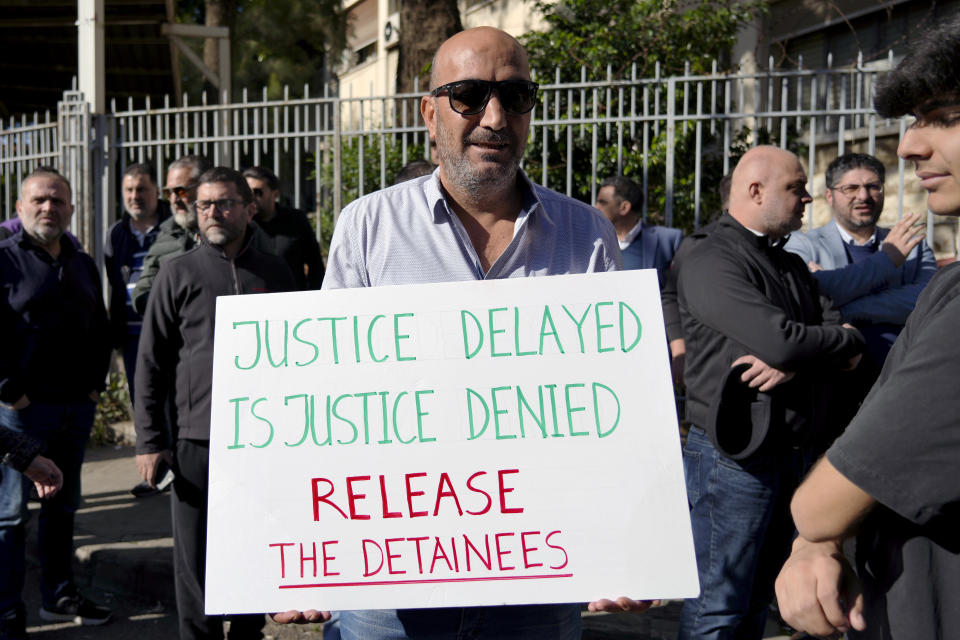 A relative of detainees in the Aug. 4, 2020 Beirut port blast investigation holds a placard during a protest in front of the Justice Palace in Beirut, Lebanon, Jan. 19, 2023. The judge Tarek Bitar investigating Beirut's massive 2020 port blast resumed work Monday, Jan. 23, 2023 after a nearly 13-month halt, ordering the release of some detainees and announcing plans to charge others, including two top generals, judicial officials said. (AP Photo/Bilal Hussein)