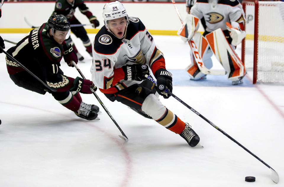 Anaheim Ducks defenseman Pavel Mintyukov (34) beats Arizona Coyotes forward Dylan Guenther (11) during a preseason NHL hockey game, Sunday, Sept. 25, 2022 in Tucson, Ariz. (Rebecca Sasnett/Arizona Daily Star via AP)