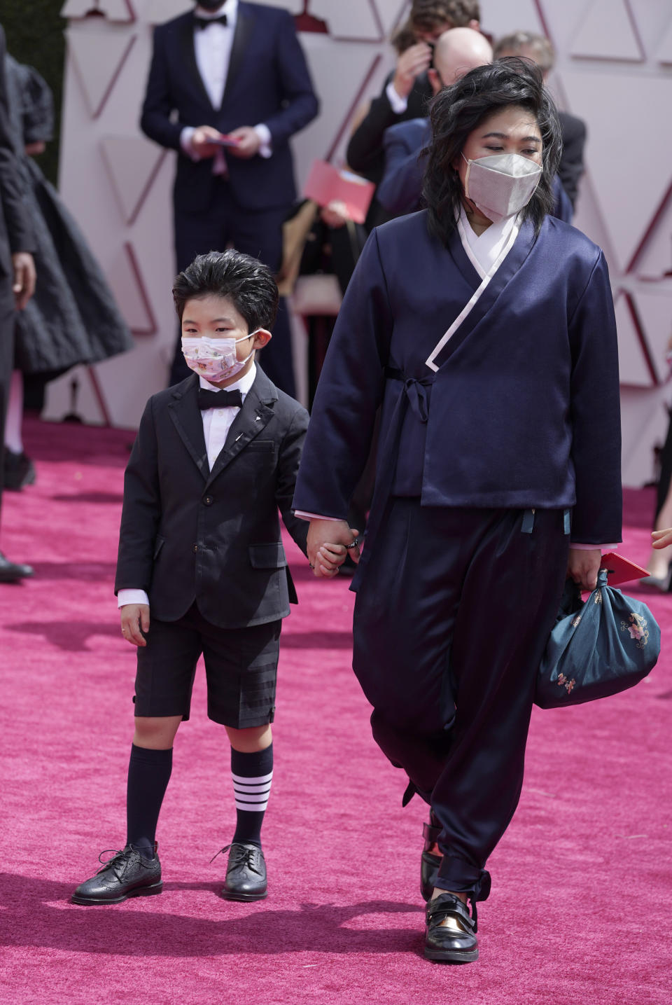 CORRECTS NAME OF WOMAN AT RIGHT TO CHRISTINA OH - Alan S. Kim, left, and Christina Oh arrive at the Oscars on Sunday, April 25, 2021, at Union Station in Los Angeles. (AP Photo/Chris Pizzello, Pool)