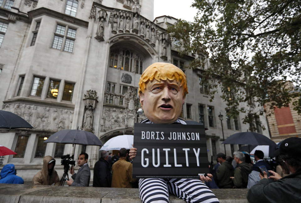 A person dressed as a caricature of British Prime Minister Boris Johnson in a prison uniform stands outside the Supreme Court in London, Tuesday, Sept. 24, 2019 after it made it's decision on the legality of Johnson's five-week suspension of Parliament. In a setback for Johnson, Britain's Supreme Court has ruled that the suspension of Parliament was illegal. The ruling Tuesday is a major blow to the prime minister who had suspended Parliament for five weeks, claiming it was a routine closure. (AP Photo/Matt Dunham)