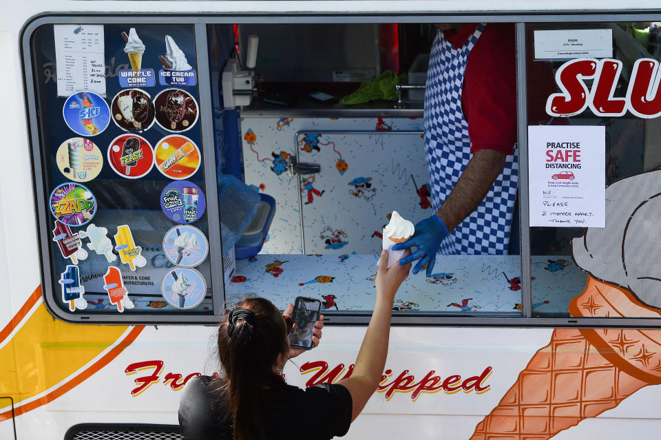 People queue for ice-cream on the Thames path near Hammersmith, London, as the UK continues in lockdown to help curb the spread of the coronavirus.