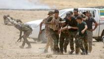 Iraqi Shi'ite paramilitaries help a wounded fighter after clashes with Islamist State militants in al Nibaie, in Anbar province May 26, 2015. REUTERS/Stringer