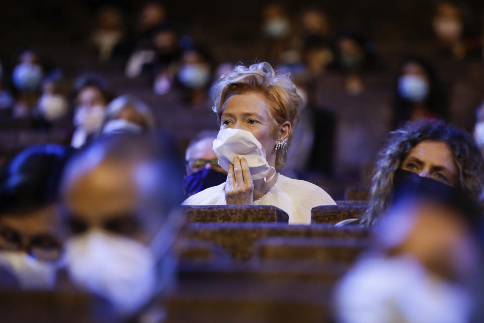 FILE - Actress Tilda Swinton wears a mask as she sits in the auditorium during the opening ceremony of the 77th edition of the Venice Film Festival in Venice, Italy, on Sept. 2, 2020. This year, three of the four major fall film festivals, including Venice, are going forward despite the pandemic. Those in Venice acknowledge it hasn’t been anywhere near the same. Masked moviegoers in set-apart seats. A barrier walls off the red carpet to discourage crowds of onlookers. Greetings are kiss-less. A little bit of the romance of movies has gone out. (AP Photo/Domenico Stinellis, File)