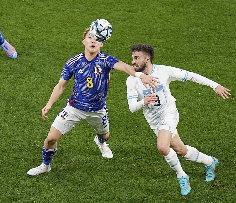 Le Japonais Ritsu Doan, à gauche, et l'Uruguayen Diego Rossi se battent pour le ballon lors de la première mi-temps de leur match de football amical au stade national de Tokyo, le vendredi 24 mars 2023. (Kyodo News via AP)