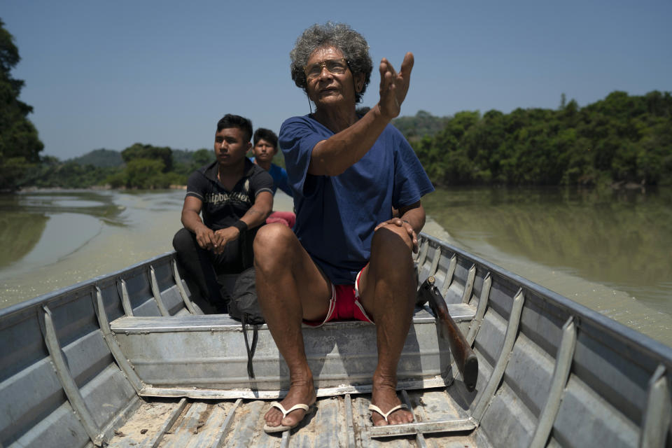 In this Aug. 27, 2019 photo, Wakonkra Kayapo of the Kayapo indigenous community, rifle in tow, indicates the way on the Curua River as he searches for suspected prospectors and loggers in the Bau indigenous reserve in Altamira, in Brazil's Amazon, where fires burn nearby. "The forest will stay in its place. It can't be taken down. We take care of the land", said the 68-year-old man who describes himself as a "small warrior." (AP Photo/Leo Correa)