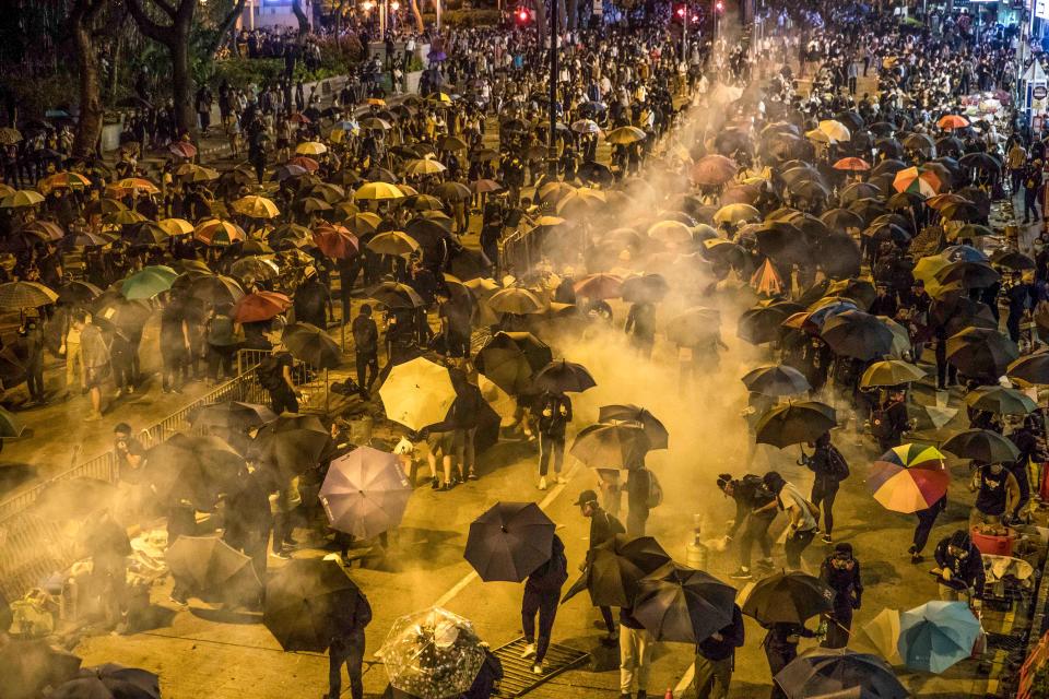 Protesters react as police fire tear gas while they attempt to march towards Hong Kong Polytechnic University in Hung Hom district of Hong Kong on November 18, 2019. - Dozens of Hong Kong protesters escaped a two-day police siege at a campus late on November 18 by shimmying down a rope from a bridge to awaiting motorbikes in a dramatic and perilous breakout that followed a renewed warning by Beijing of a possible intervention to end the crisis engulfing the city. (Photo by DALE DE LA REY / AFP) (Photo by DALE DE LA REY/AFP via Getty Images)