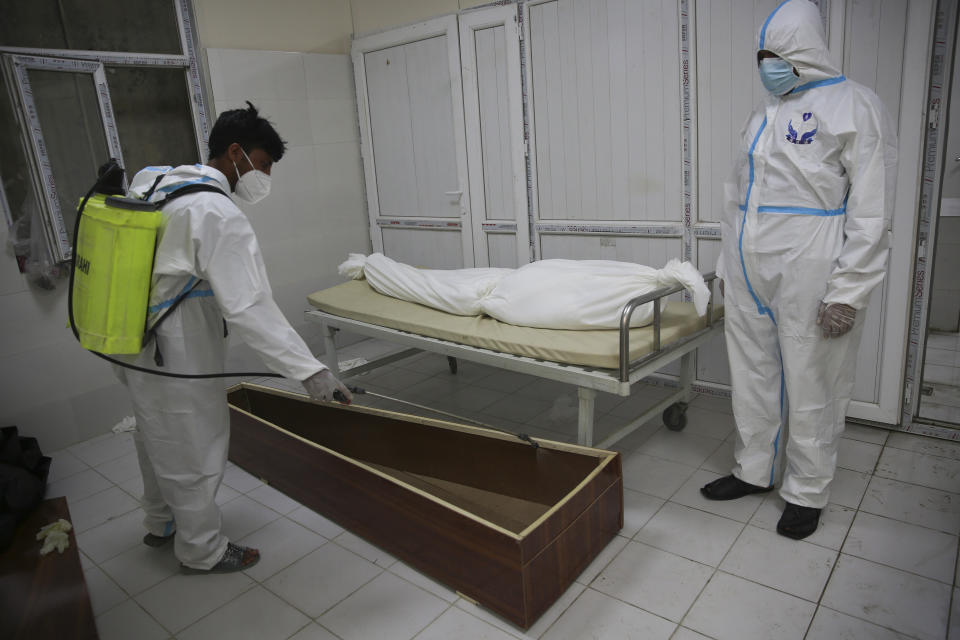 Afghan health workers in protective suits spray disinfectant on the coffin of a person who died from COVID-19 at the Afghan-Japan Communicable Disease Hospital in Kabul, Afghanistan, Tuesday June 30, 2020. (AP Photo/Rahmat Gul)