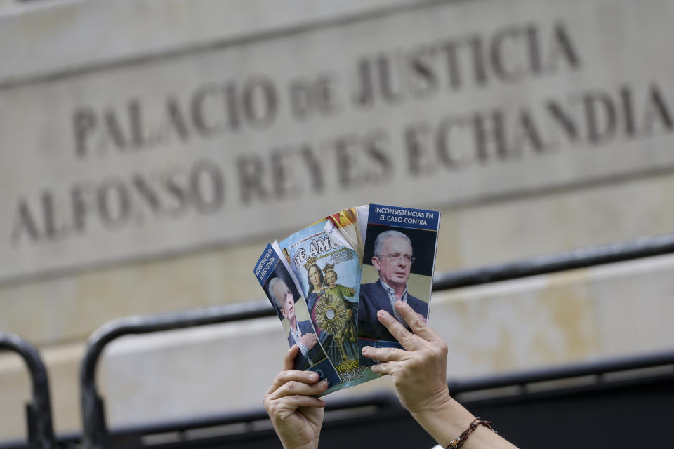 A supporter of former president Alvaro Uribe holds pamphlets in support of of him, in front of the Supreme Court during his hearing in an investigation for witness tampering, in Bogota, Colombia, Tuesday, Oct. 8, 2019. Uribe is being investigated for allegedly trying to influence and possibly bribe members of a former paramilitary group. (AP Photo/Ivan Valencia)