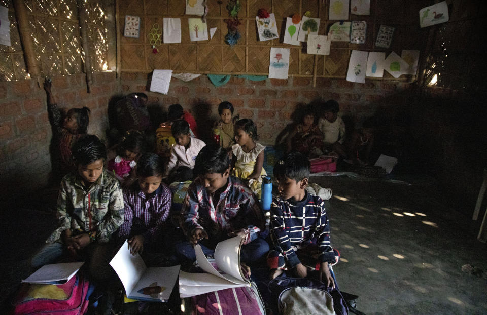 Imradul Ali, 10, second from left, studies with other students at a school near a landfill on the outskirts of Gauhati, India, Friday, Feb. 5, 2021. Once school is done for the day, Ali, rushes home to change out of his uniform so that he can start his job as a scavenger in India’s remote northeast. Coming from a family of scavengers or “rag pickers," Ali started doing it over a year ago to help his family make more money. Ali says he doesn’t want to spend his life doing this, but he doesn’t know what the future holds. (AP Photo/Anupam Nath)