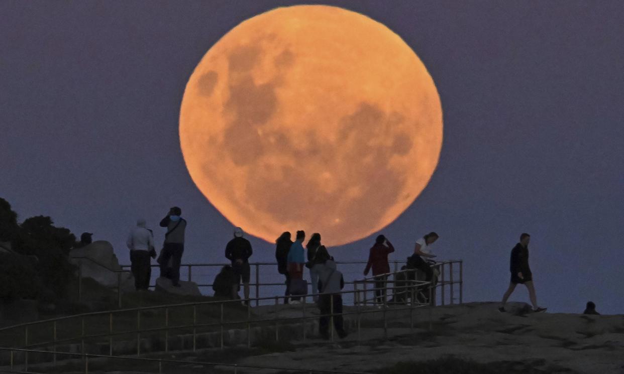 <span>People watch as the full ‘super flower blood moon’ rises over Bondi Beach in Sydney on 26 May, 2021. Guardian Australia’s picture editor explains how to photograph the moon, whether you’re using a phone or DSLR camera, and the best settings to use.</span><span>Photograph: Anadolu Agency/Getty Images</span>