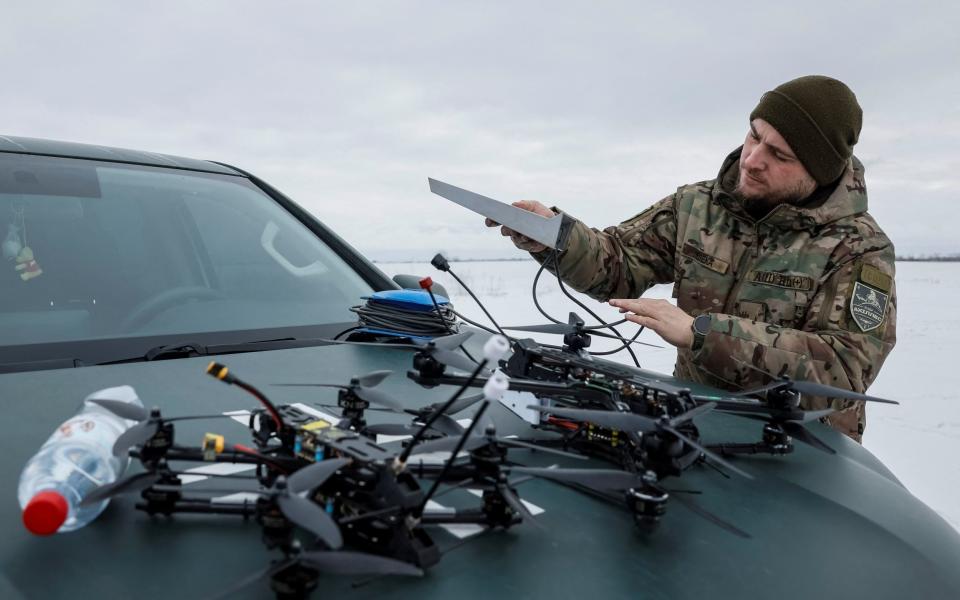 A fellow Ukrainian serviceman of the "Achilles" Attack Drone Battalion monitors his equipment in practice