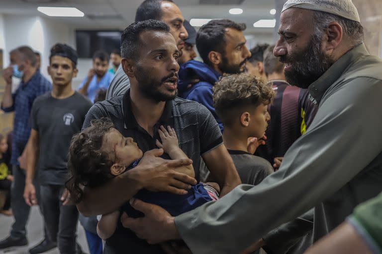 Un palestino llevando a un niño herido en el bombardeo israelí espera tratamiento en el Hospital Shifa.