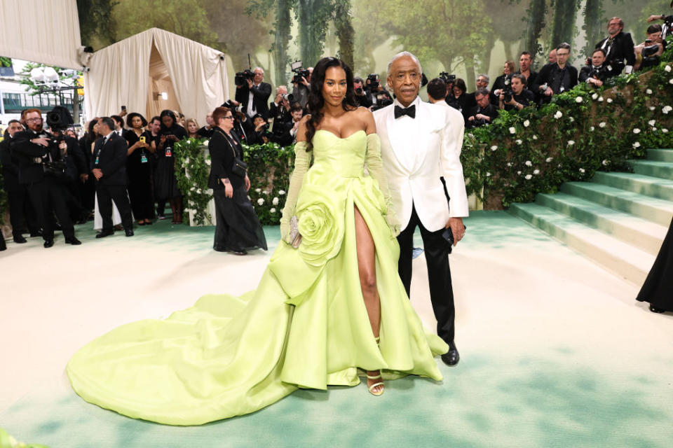 Aisha in a gown with a train and Al in a classic suit at a gala event