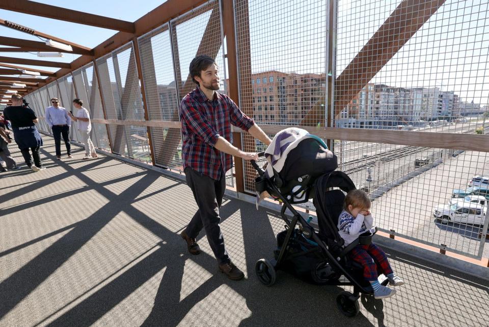 Davey Davis pushes Elliot Davis across a new pedestrian bridge at 300 North and 490 West, that crosses two Utah Transit Authority and three Union Pacific rail lines, in Salt Lake City on Wednesday. The crossing is on a route heavily used by West High School students walking to and from school.