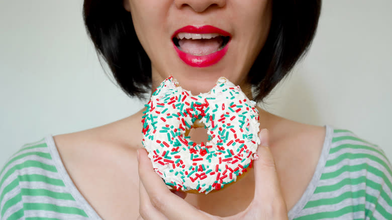 woman biting glazed donut
